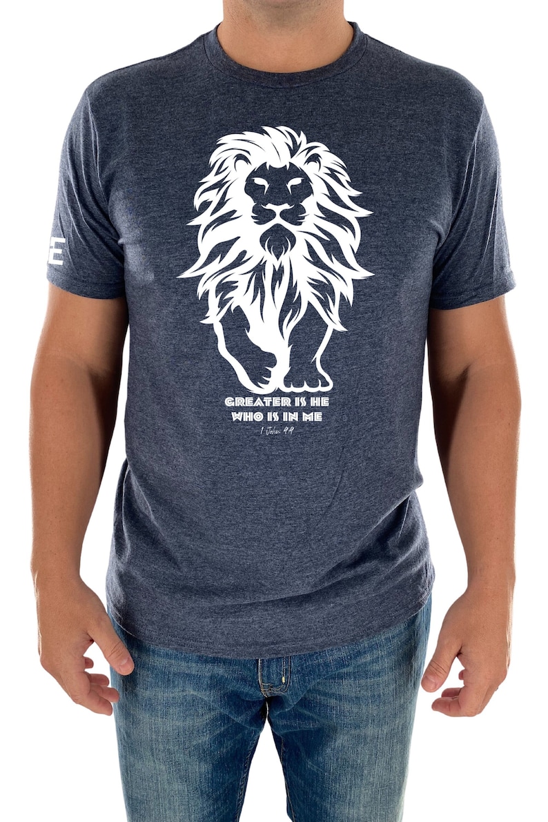 May include: A navy blue t-shirt with a white graphic of a lion and the text "GREATER IS HE WHO IS IN ME - 1 John 4:4".