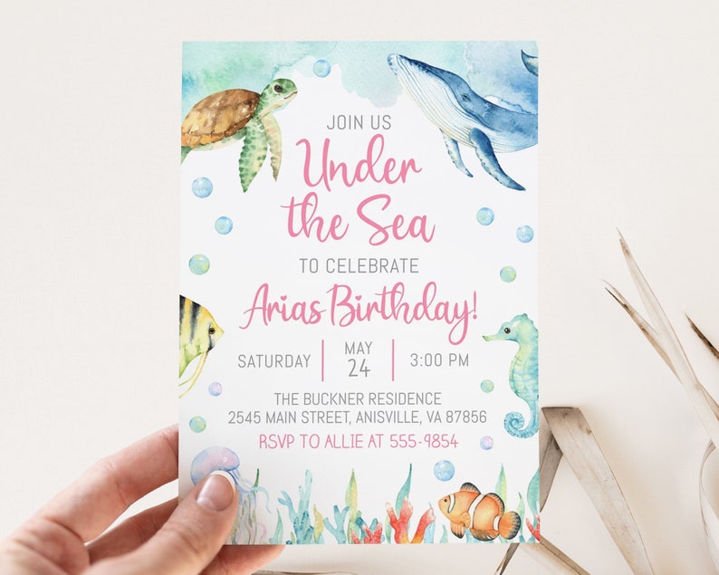 May include: Under the Sea birthday party invitation with watercolor illustrations of a whale, turtle, seahorse, jellyfish, and clownfish. The invitation is printed on white cardstock and includes the text "Join us Under the Sea to celebrate Arias Birthday!" with the date and time of the party.