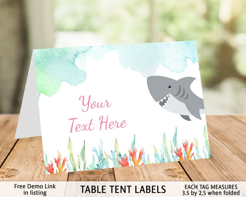 May include: Table tent labels with a watercolor background featuring a shark swimming in the ocean. The labels are 3.5 inches by 2.5 inches when folded. The text "Your Text Here" is in pink.