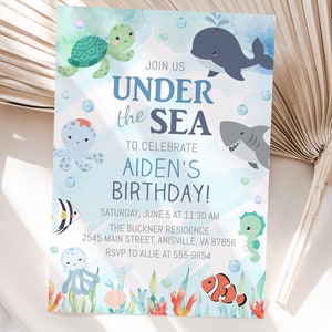 May include: A blue and white invitation card with a watercolor background featuring sea creatures like a turtle, octopus, whale, shark, and seahorse. The text on the card reads "Join us Under the Sea to celebrate Aiden's Birthday!" with details about the event.