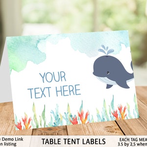 May include: Table tent labels with a watercolor background featuring a blue whale and coral. The text "YOUR TEXT HERE" is printed on the label. Each tag measures 3.5 by 2.5 inches when folded.