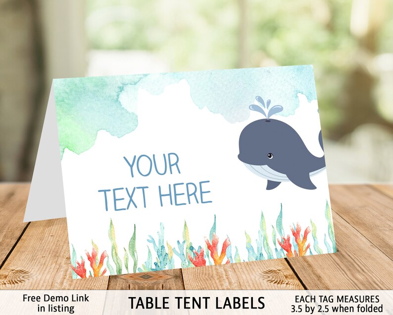 May include: Table tent labels with a watercolor background featuring a blue whale and coral. The text "YOUR TEXT HERE" is printed on the label. Each tag measures 3.5 by 2.5 inches when folded.