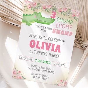 May include: A pink and green birthday invitation with a cartoon alligator and floral accents. The invitation reads "Chomp Chomp Swamp" and "Olivia is turning three!" with details for the party on Saturday, July 22, 2022 at 3:00 PM.