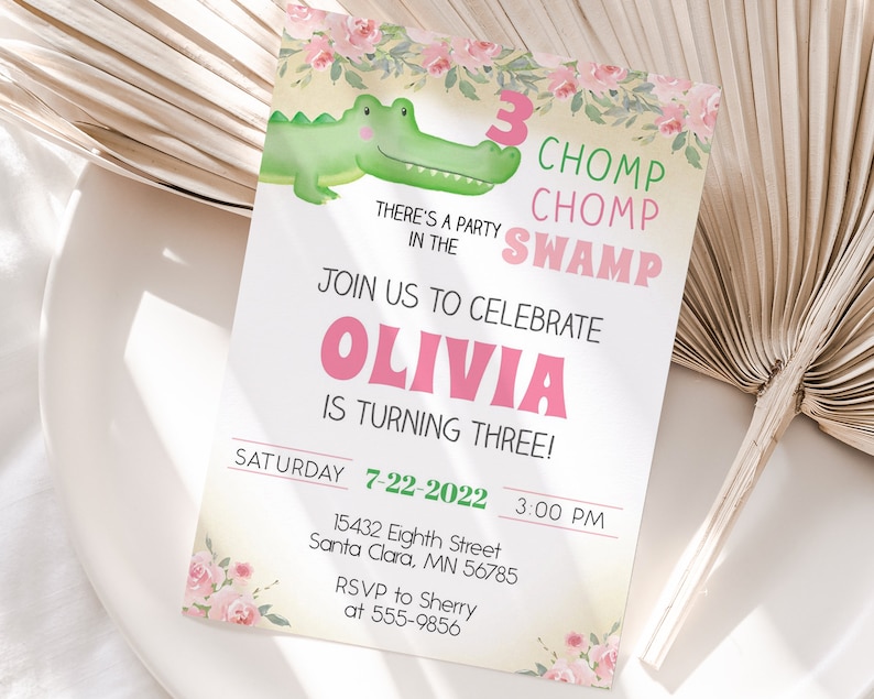 May include: A pink and green birthday invitation with a cartoon alligator and floral accents. The invitation reads "Chomp Chomp Swamp" and "Olivia is turning three!" with details for the party on Saturday, July 22, 2022 at 3:00 PM.