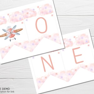 K&ouml;nnte beinhalten: Rosa-wei&szlig;er druckbarer Banner mit dem Wort "ONE" in rosa Buchstaben. Der Banner zeigt ein Aquarelldesign mit Wolken und Blumen. Ein kleines Flugzeug ist auf dem ersten Banner abgebildet.