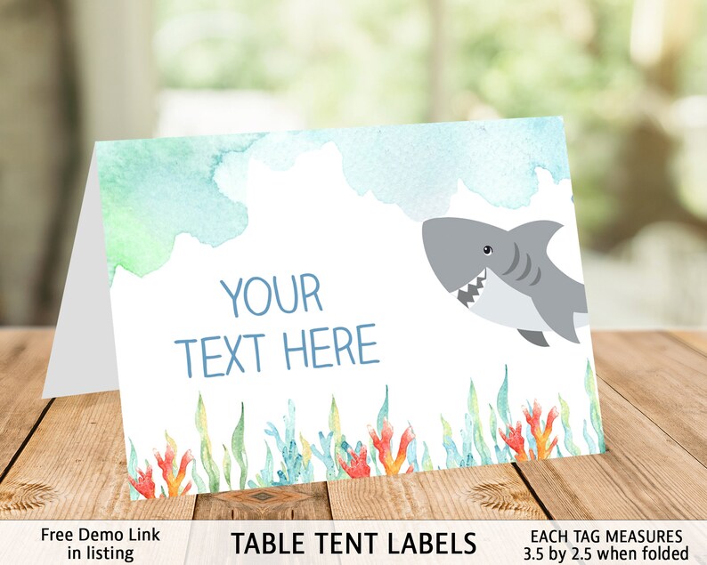 May include: Table tent labels with a watercolor background featuring a shark swimming in the ocean. The labels are 3.5 inches by 2.5 inches when folded and have the text "YOUR TEXT HERE" in blue.
