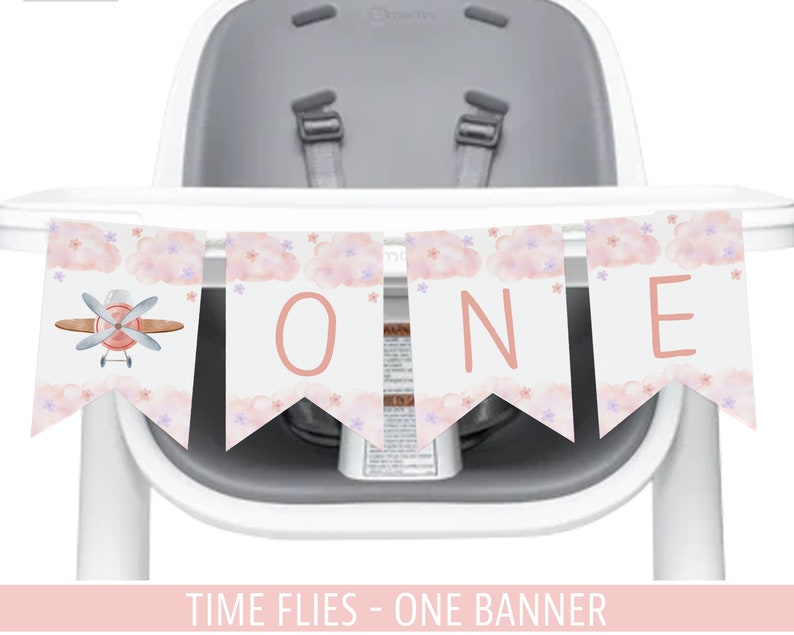 K&ouml;nnte beinhalten: Ein rosa-wei&szlig;er Hochstuhl-Banner mit Wolken und einem rosa Flugzeug. Der Banner sagt "ONE" und "TIME FLIES - ONE BANNER".