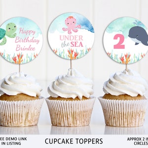 May include: Set of three 2 inch round cupcake toppers featuring an octopus, a whale, and a turtle with the text "Happy Birthday Brinlee" and "Under the Sea".