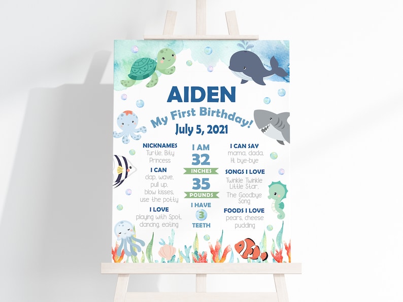 Puede incluir: Un cartel de primer cumplea&ntilde;os de estilo acuarela azul y verde con tem&aacute;tica de criaturas marinas. El cartel presenta el nombre Aiden, la fecha 5 de julio de 2021, y detalles sobre el primer a&ntilde;o del ni&ntilde;o, incluyendo su altura, peso, alimentos y canciones favoritos.