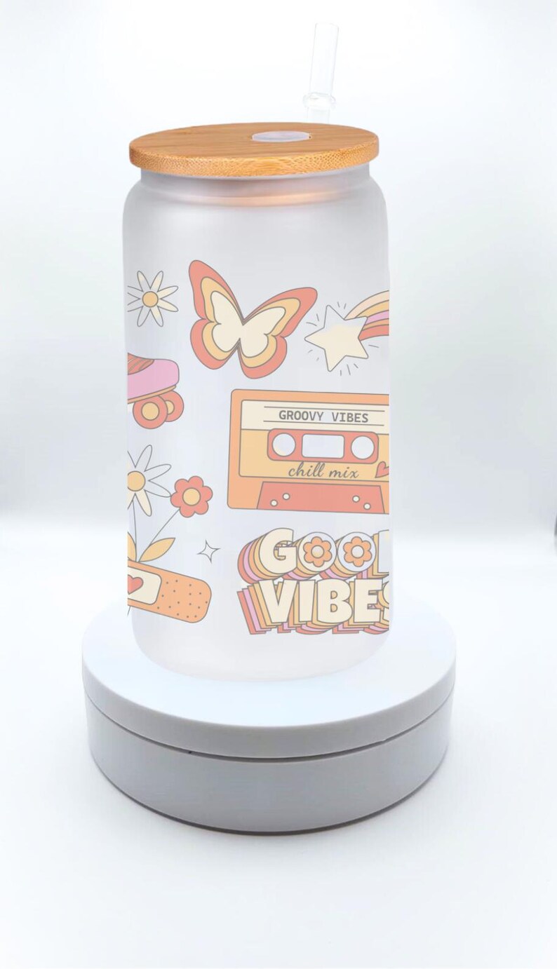 May include: A frosted glass water bottle with a bamboo lid and a straw. The bottle has a retro design with a butterfly, a cassette tape, a roller skate, and the words "Good Vibes" and "Groovy Vibes chill mix".