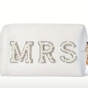 May include: White zippered cosmetic bag with the word "MRS" spelled out in pearl-like embellishments.