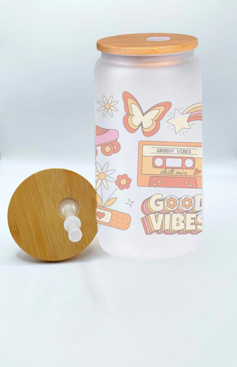 May include: A frosted glass water bottle with a bamboo lid and straw. The bottle has a retro design with a butterfly, roller skates, a cassette tape, and the text "Groovy Vibes chill mix" and "Good Vibes".