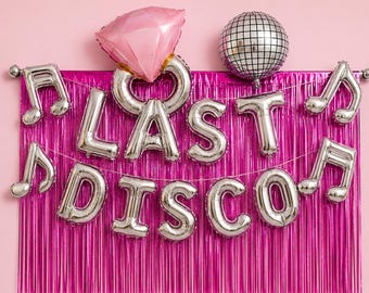 Op de afbeelding: Een feestdecoratieset met een roze diamantvormige ballon, een zilveren discobal en zilveren folieballonnen met de tekst "LAST DISCO". Muzieknotenballonnen en een roze franjesachtergrond maken de feestelijke scène compleet.