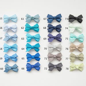May include: A collection of colorful ribbon bows in various shades of blue, green, gray, and beige. Each bow is numbered from 55 to 78, with a range of colors from light blue to dark navy, and other colors like black, gray, and beige.