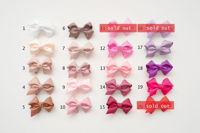 May include: A collection of satin hair bows in various colors, including white, beige, pink, and purple. Some bows are marked as "sold out". These bows are suitable for various occasions and styles.