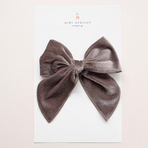 May include: A large, gray velvet bow. The bow is tied in a classic style with two loops and a center knot.