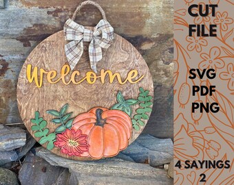 May include: A round wooden sign with a welcome sign, a pumpkin, leaves, and a plaid bow. The sign is on a background of rocks.