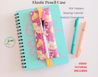 May include: A rectangular fabric pencil case with a pink and orange floral pattern and a white zipper, attached to a light blue spiral-bound notebook with an elastic band. The text Elastic Pencil Case, PDF Pattern, Sewing Tutorial, Instant Download, and Video Tutorial Included are visible.