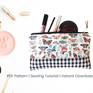 May include: A white zippered pouch with a black and white checkered bottom. The pouch is decorated with a colorful butterfly print. The pouch is open and has makeup brushes and a compact inside. The text "PDF Pattern | Sewing Tutorial | Instant Download" is below the pouch.