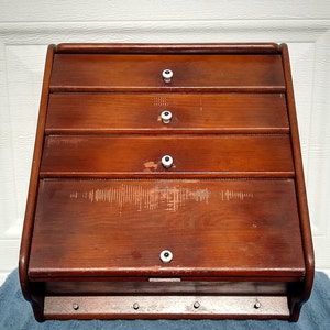 Puede incluir: Una panera de madera vintage con cuatro cajones y pomos de porcelana blanca. La panera tiene un acabado desgastado y est&aacute; hecha de madera maciza.