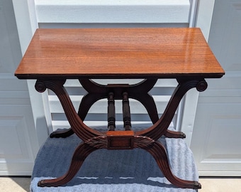 May include: A rectangular, wooden side table with a rich, reddish-brown finish. The table features a decorative, curved leg design with carved details and a lower support. The table measures approximately 30 inches long.