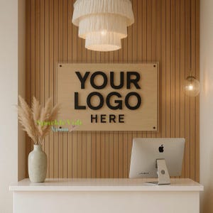 May include: A modern office reception area with a white desk, a computer, and a wooden wall. A sign on the wall reads "YOUR LOGO HERE" in black letters. A decorative light fixture hangs from the ceiling, and a vase of dried flowers sits on the desk.