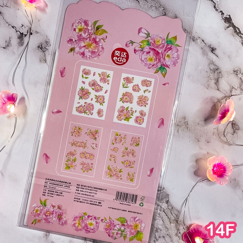 Pu&ograve; includere: Un foglio di adesivi rosa con disegni floreali. Il foglio include adesivi di peonie rosa di varie dimensioni, con foglie verdi e alcuni petali sciolti. Il marchio "eda" &egrave; visibile. L'angolo in basso a destra ha il testo "14F".