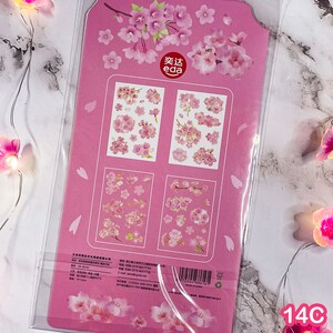 Pu&ograve; includere: Foglio di adesivi rosa con disegni di fiori di ciliegio. Il foglio include varie dimensioni e disposizioni di adesivi di fiori di ciliegio rosa. La confezione &egrave; rosa con illustrazioni di fiori di ciliegio e il testo "eda".