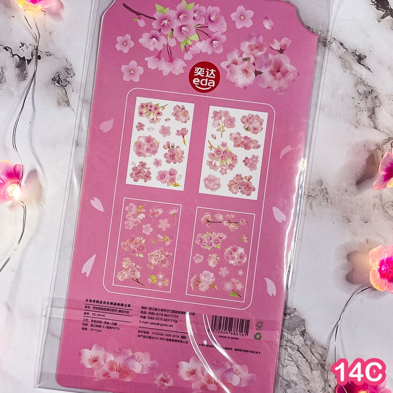 Pu&ograve; includere: Foglio di adesivi rosa con disegni di fiori di ciliegio. Il foglio include varie dimensioni e disposizioni di adesivi di fiori di ciliegio rosa. La confezione &egrave; rosa con illustrazioni di fiori di ciliegio e il testo "eda".