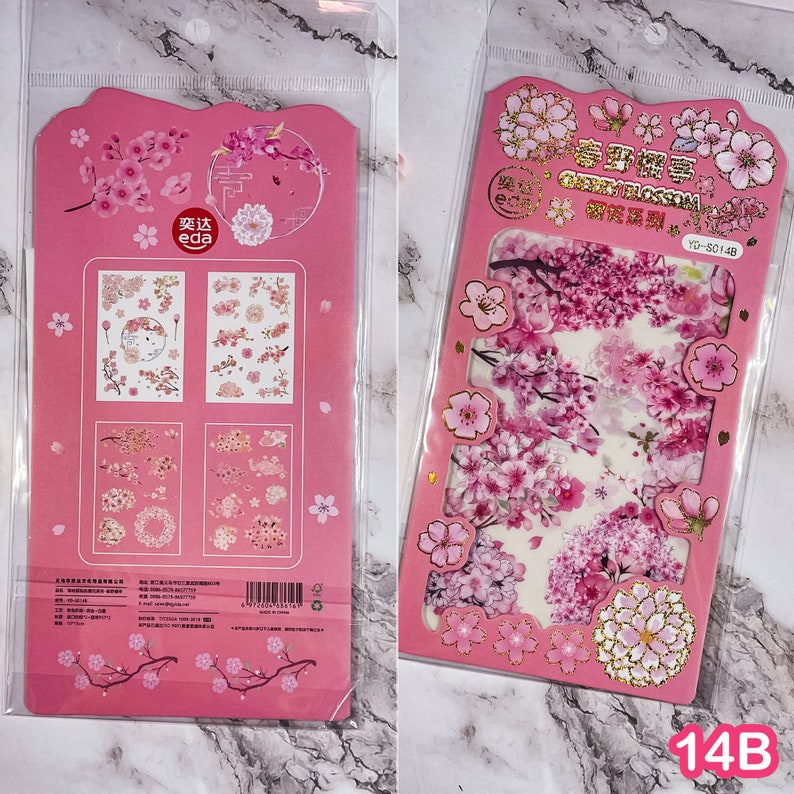 Pu&ograve; includere: Due fogli di adesivi rosa con disegni di fiori di ciliegio. Un foglio ha pi&ugrave; disegni di adesivi, e l'altro ha una grande composizione floreale. Gli adesivi sono confezionati in una custodia di plastica trasparente.