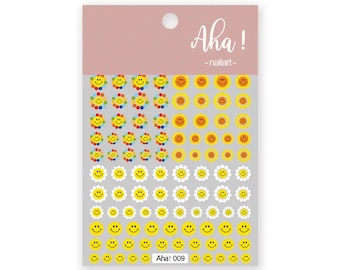 May include: Sheet of nail art stickers featuring various smiley face designs. Includes colorful flower smileys, yellow smileys, and white daisy smileys. The text "Aha! - nailart - Aha! 009" is printed on the sheet.