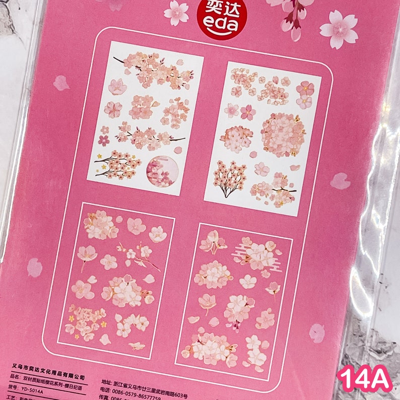 Pu&ograve; includere: Foglio di adesivi rosa con disegni di fiori di ciliegio. Gli adesivi mostrano singoli fiori, grappoli e rami in rosa e bianco. Il foglio include il testo "奕达 eda" e il numero "14A".