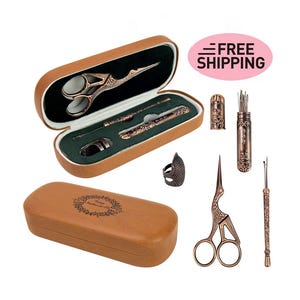 Puede incluir: Un juego de herramientas de costura en una caja de cuero marrón. El juego incluye un par de tijeras, un dedal, un enhebrador de agujas y un estuche para agujas. Las herramientas son todas de color dorado antiguo y tienen diseños intrincados.