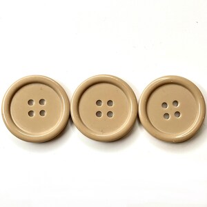 May include: Three beige plastic buttons with four holes each.