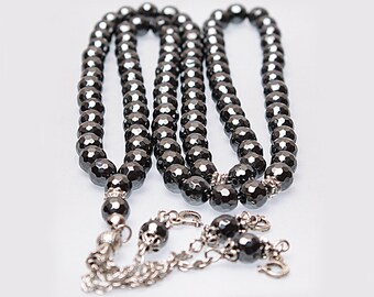 May include: A black hematite prayer bead mala with silver accents. The beads are faceted and have a dark, metallic sheen.