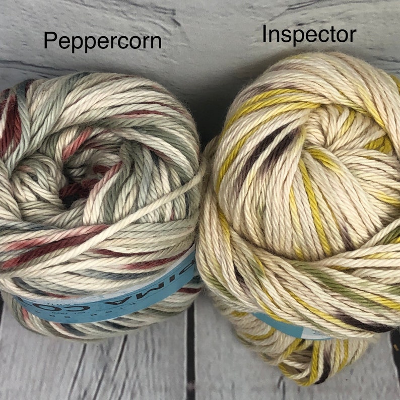 Op de afbeelding: Twee bollen garen, &eacute;&eacute;n in een groene en bruine kleurvariant genaamd "Peppercorn" en de andere in een gele en bruine kleurvariant genaamd "Inspector".