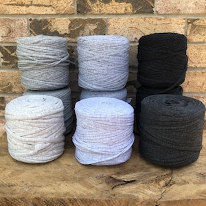 May include: Six spools of yarn in three colors: gray, light gray, and black. The yarn is made of t-shirt fabric and is perfect for crocheting or knitting.