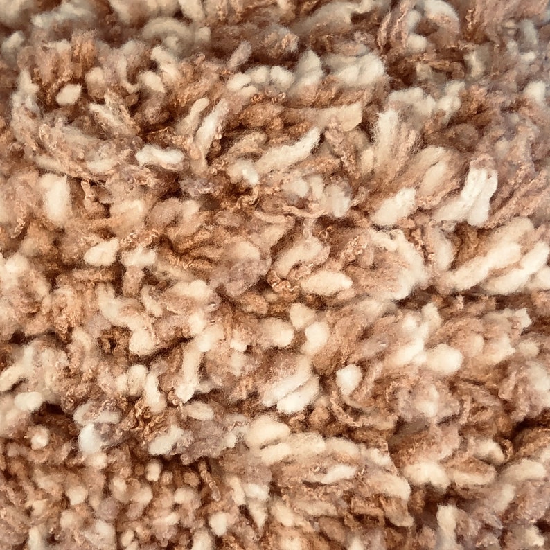 May include: Close-up of a fluffy, brown and white rug with a soft, textured surface.