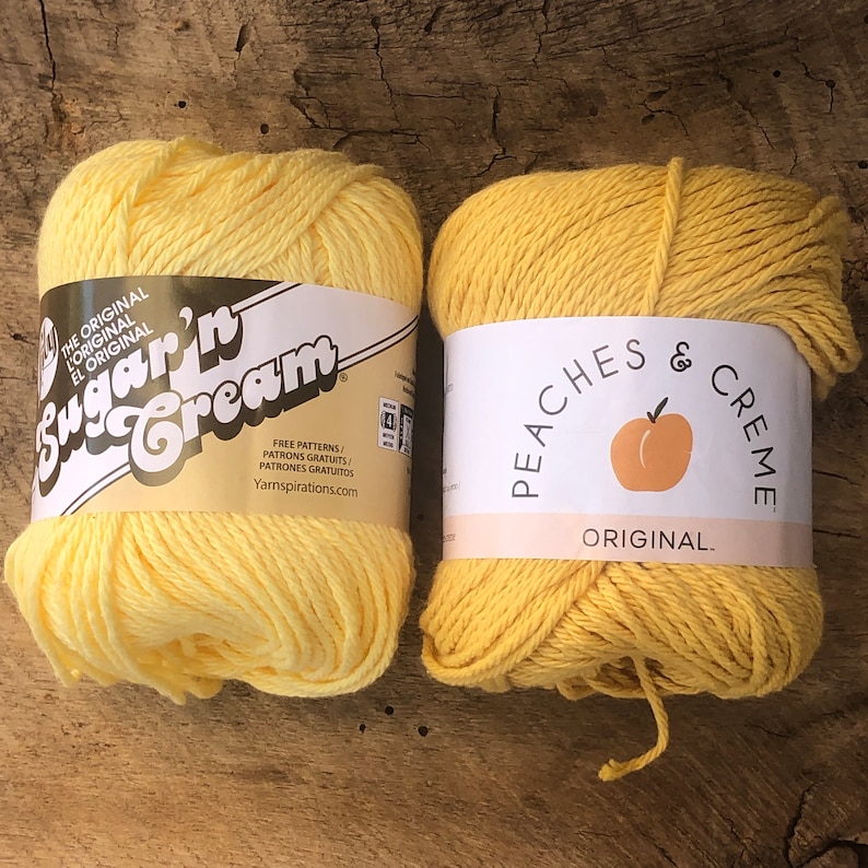 May include: Two skeins of yellow yarn, one labeled "Sugar'n Cream" and the other "Peaches & Creme". Both are labeled "The Original".