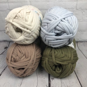 May include: Four balls of yarn in different colors: white, light gray, brown, and olive green. The yarn is made of soft, stretchy fabric and is perfect for crocheting or knitting.