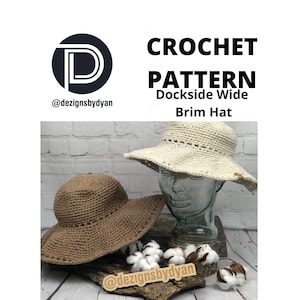 May include: Two crocheted hats with wide brims. One hat is brown and the other is white. The hats are displayed on a wooden surface with cotton bolls. The image includes the text "CROCHET PATTERN Dockside Wide Brim Hat" and the social media handle "@dezignsbydyan".