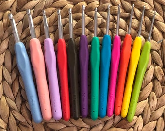 Peut inclure: Un ensemble de 10 crochets à crochet colorés, allant de 3,5 mm à 8,0 mm. Les crochets sont disposés en demi-cercle sur une surface tissée.
