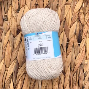 Op de afbeelding: Een bol beige katoenen garen met een blauw etiket waarop "099R VINTAGE VINTAGE" en "Made in Turkey Fabriqu&eacute; en Turquie" staat.