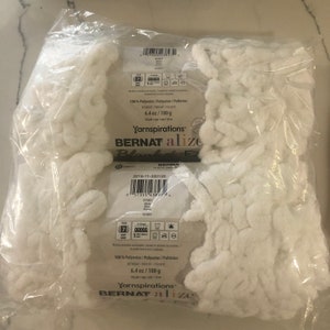 May include: A white bag of Bernat Alize Blanket-EZ yarn. The bag is labeled with the yarn's name, weight (6.4 oz / 180 g), and fiber content (100% polyester).