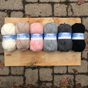May include: Six skeins of Patons Classic Wool roving yarn in a variety of colours, including white, beige, pink, grey, charcoal, and black. Each skein has a blue label with the brand name and "Classic Wool Roving" printed on it.