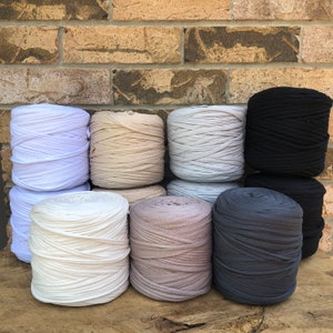 May include: Eight spools of yarn in various shades of beige, gray, and black. The yarn is made of a soft, stretchy material and is perfect for crocheting or knitting.