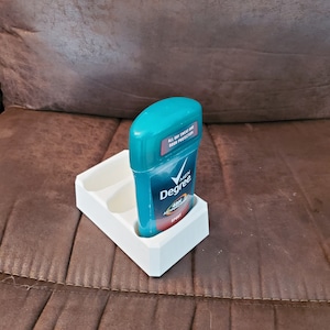 Può includere: Porta-deodorante in plastica bianca con due scomparti per stick di deodorante. Uno stick di deodorante blu e bianco è in uno degli scomparti. Lo stick di deodorante ha il testo "Degree Men 48h Antiperspirant Sport".