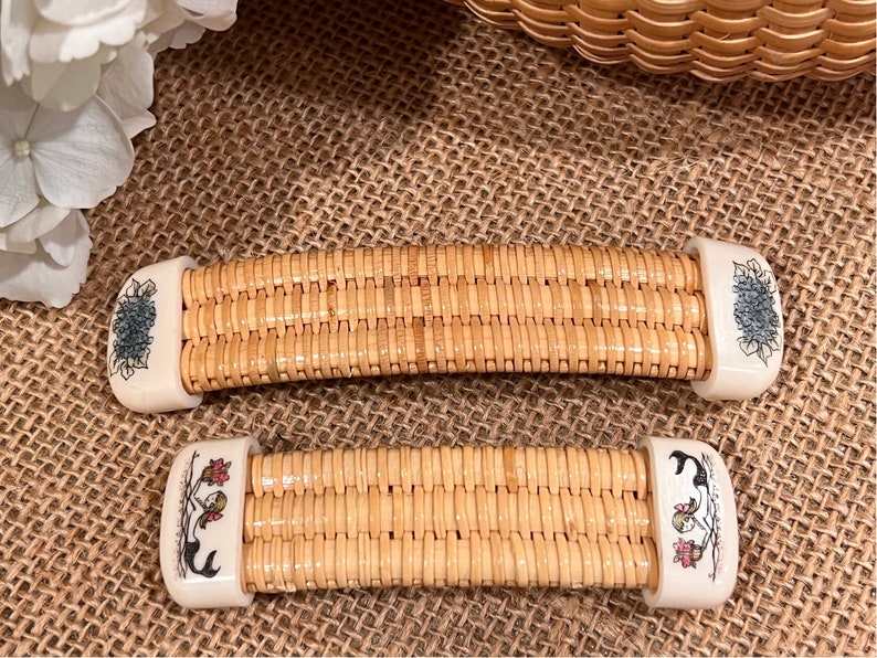 May include: Two woven wicker handles with white ceramic ends. The ends are decorated with floral designs. One handle has a blue flower design and the other has a red and green floral design.