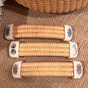May include: Three woven wicker handles with decorative ceramic ends. The ends feature floral and seashell designs in shades of blue, white, and pink.