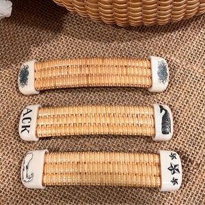 May include: Three wicker handles with white ceramic ends. The ends are decorated with different designs: a floral pattern, the letters "ACK", and a whale.